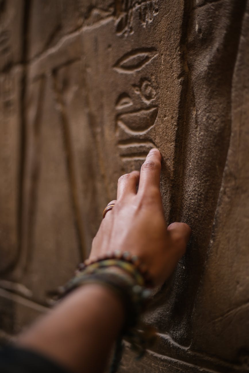 close up photo of person touching inscribed wall